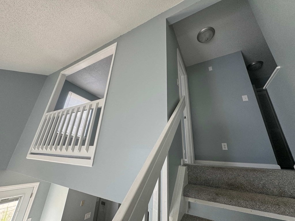 the stairwell of a home with stairs and a white railing and a window