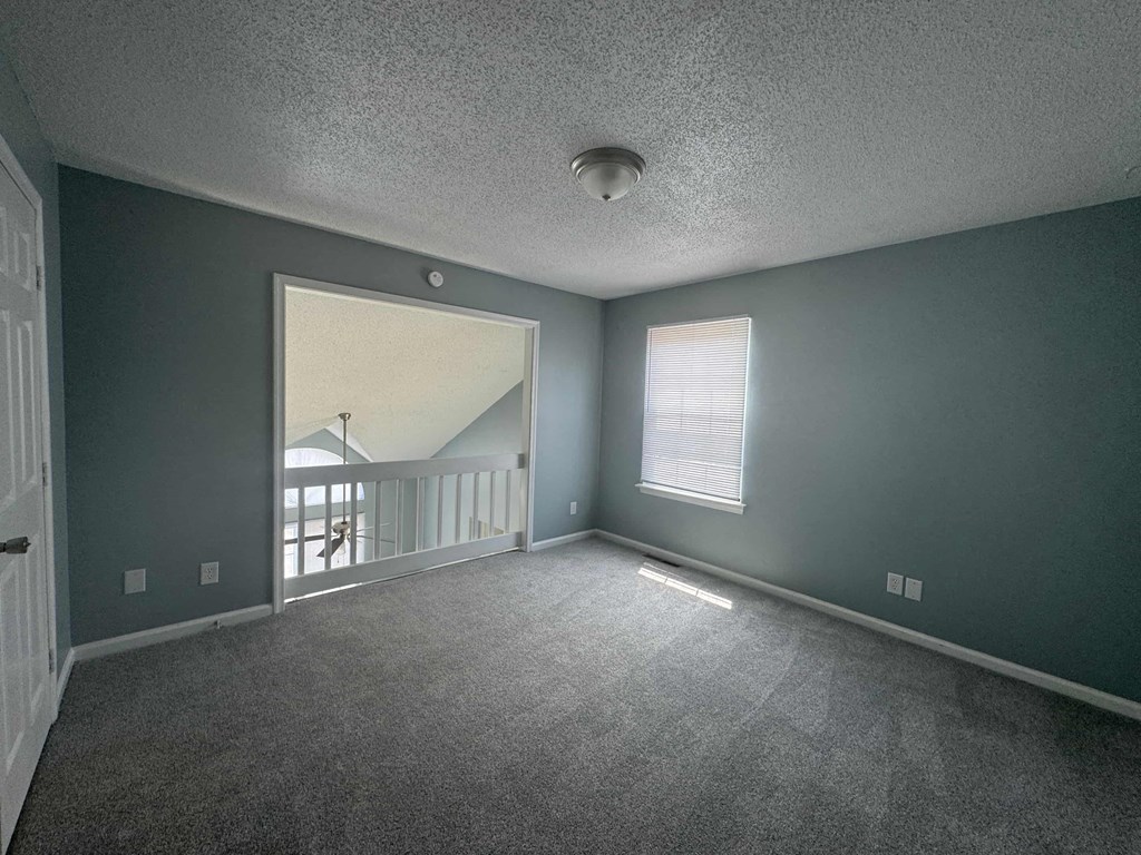 an empty living room with a large window and a balcony