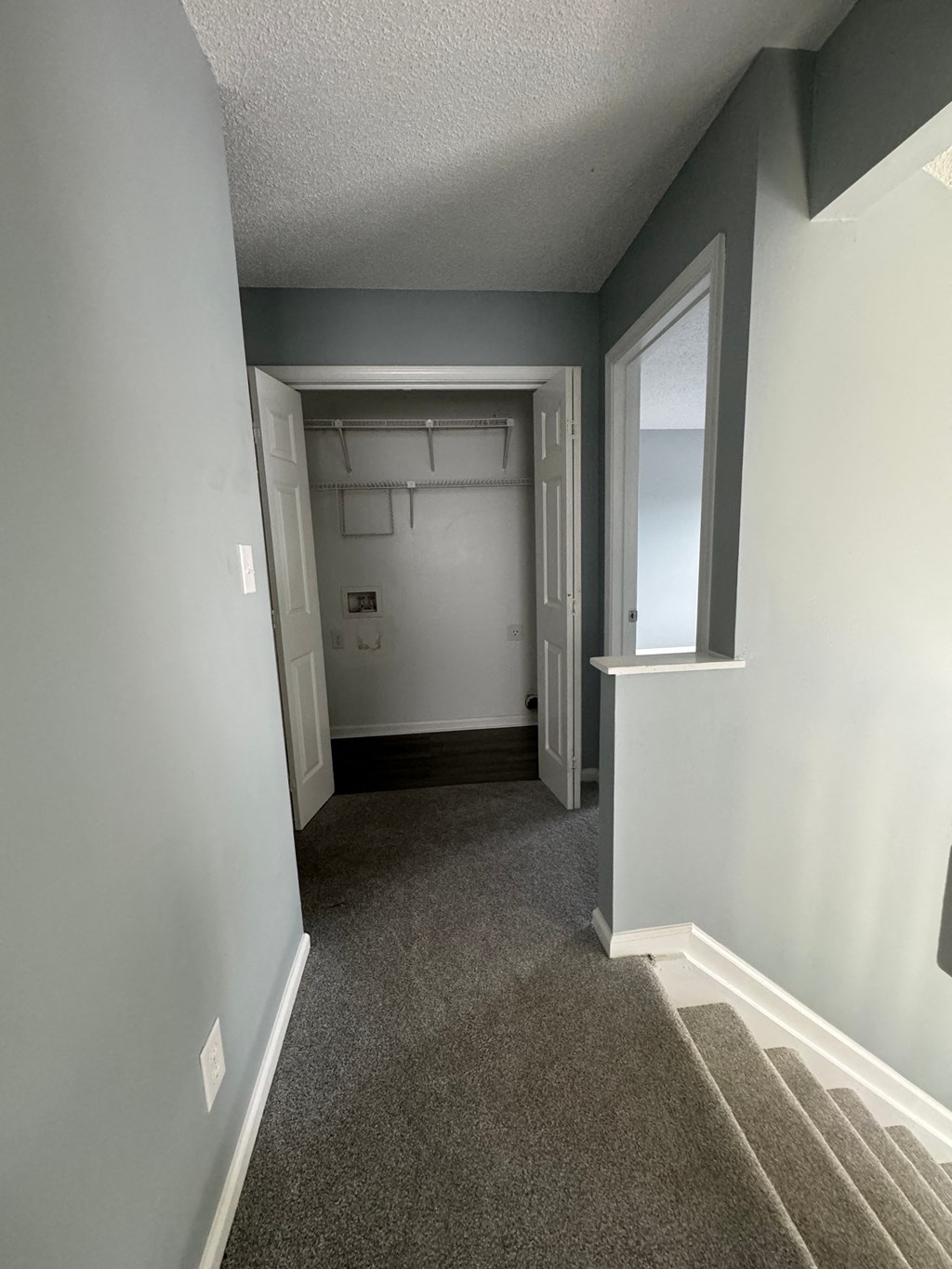 a hallway with carpeted floors and grey walls and a white door