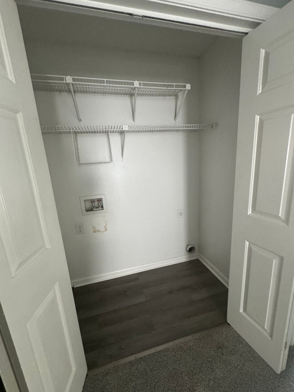 a room with a white wall and a closet with a rack on the wall