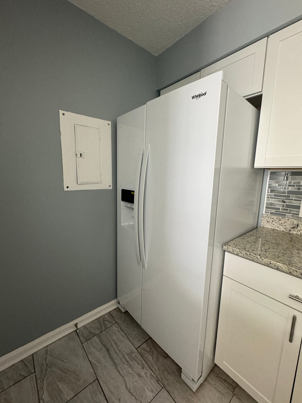 a kitchen with white cabinets and a refrigerator