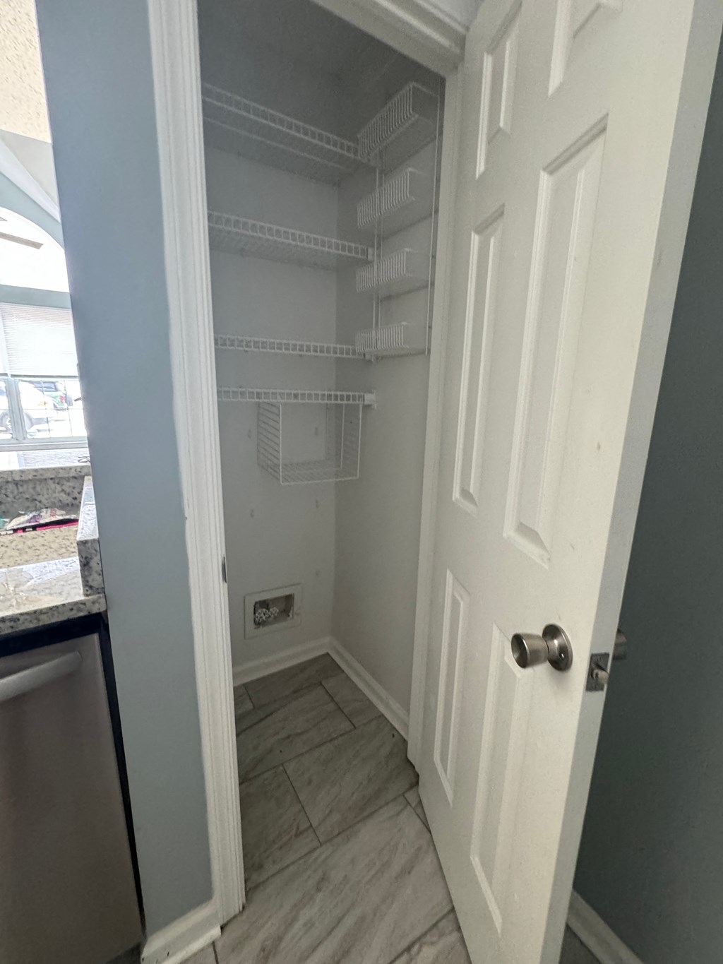 a small closet with white shelves and a door