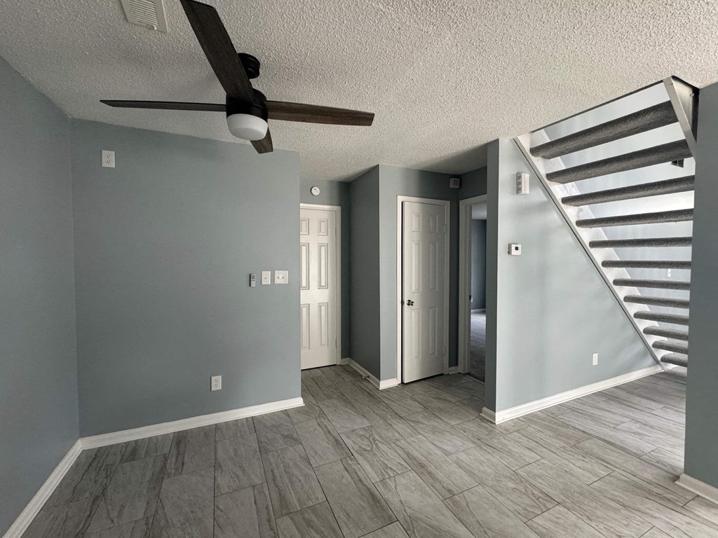 a renovated living room with stairs and a ceiling fan