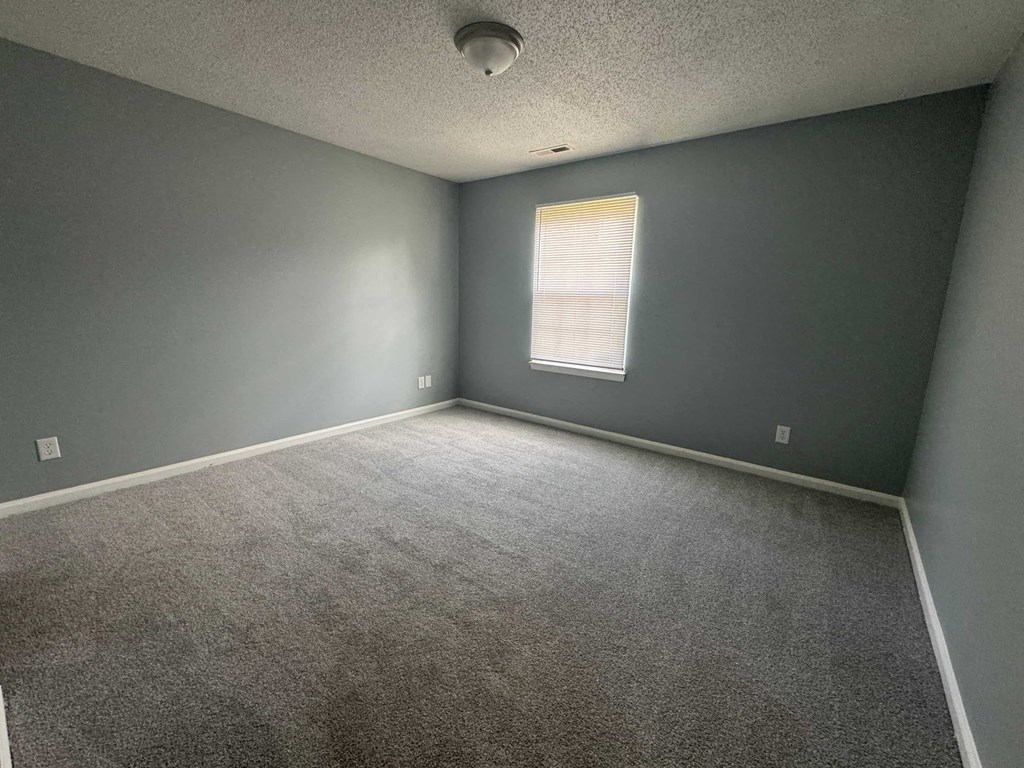 an empty room with gray walls and a window
