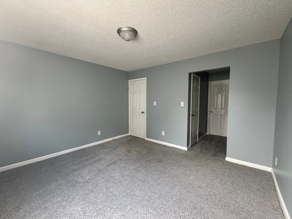 an empty living room with gray walls and gray carpet