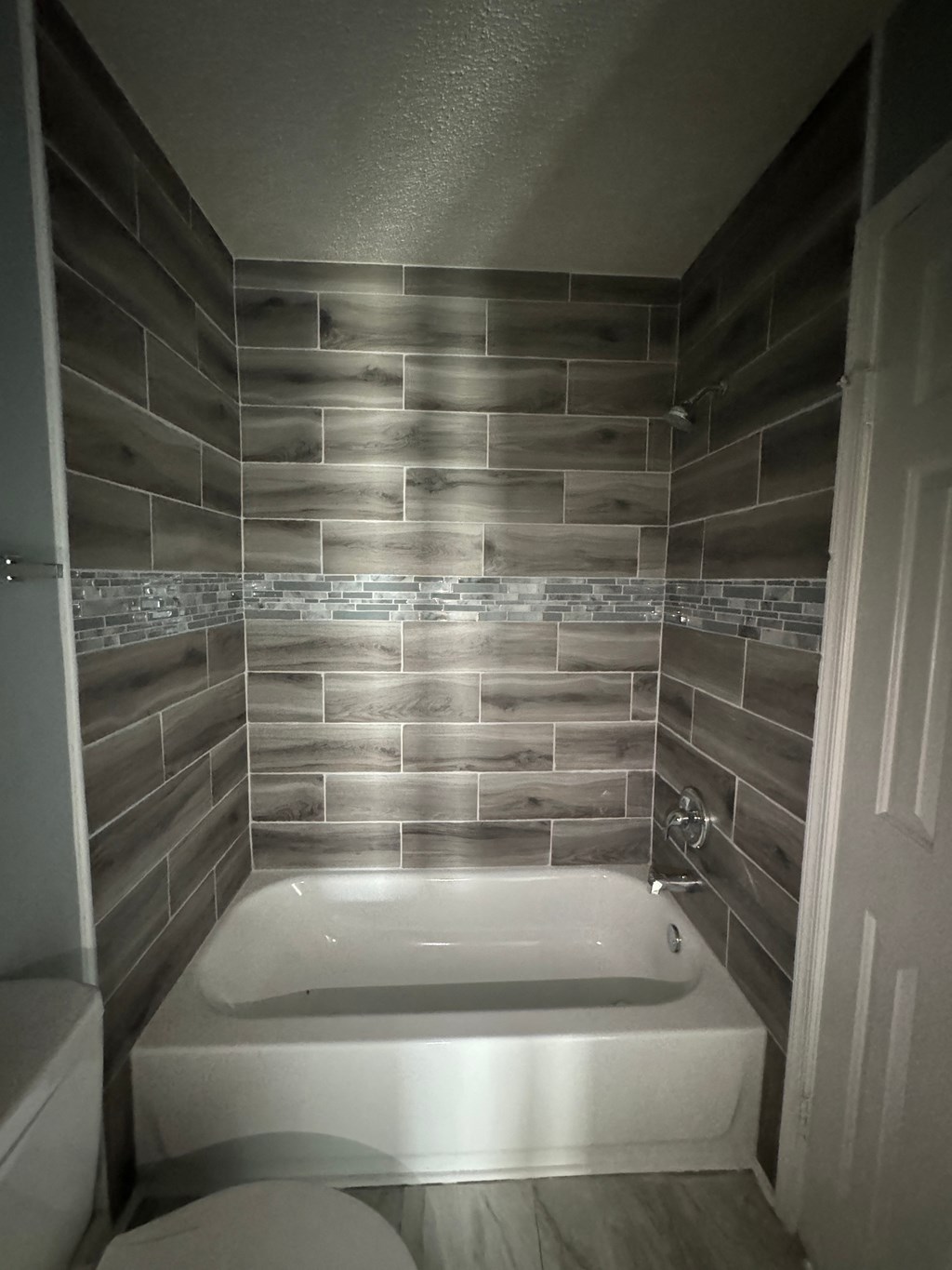 a small bathroom with a bath tub and tile walls