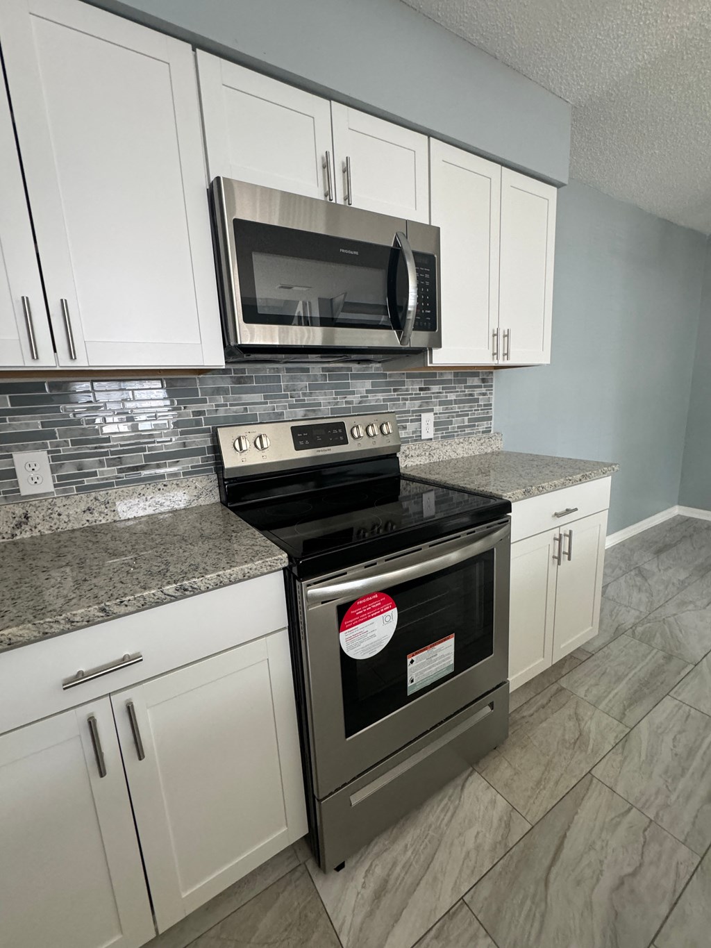 a kitchen with white cabinets and a stove and microwave