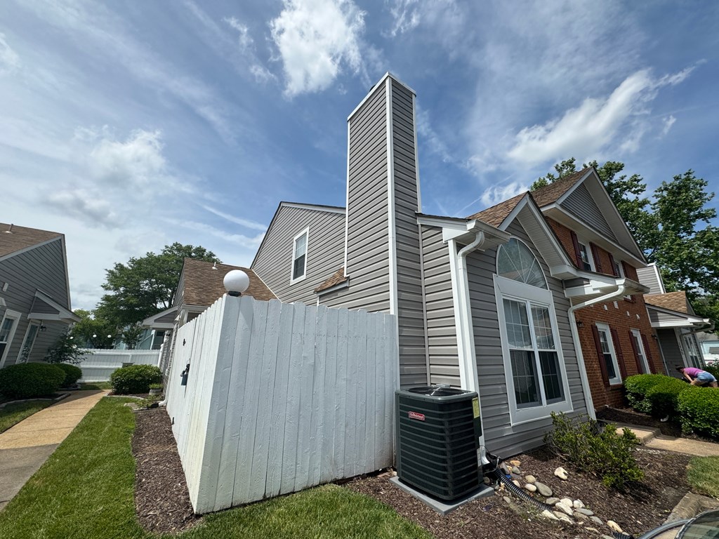 a white fence in front of a gray house with a grey roof