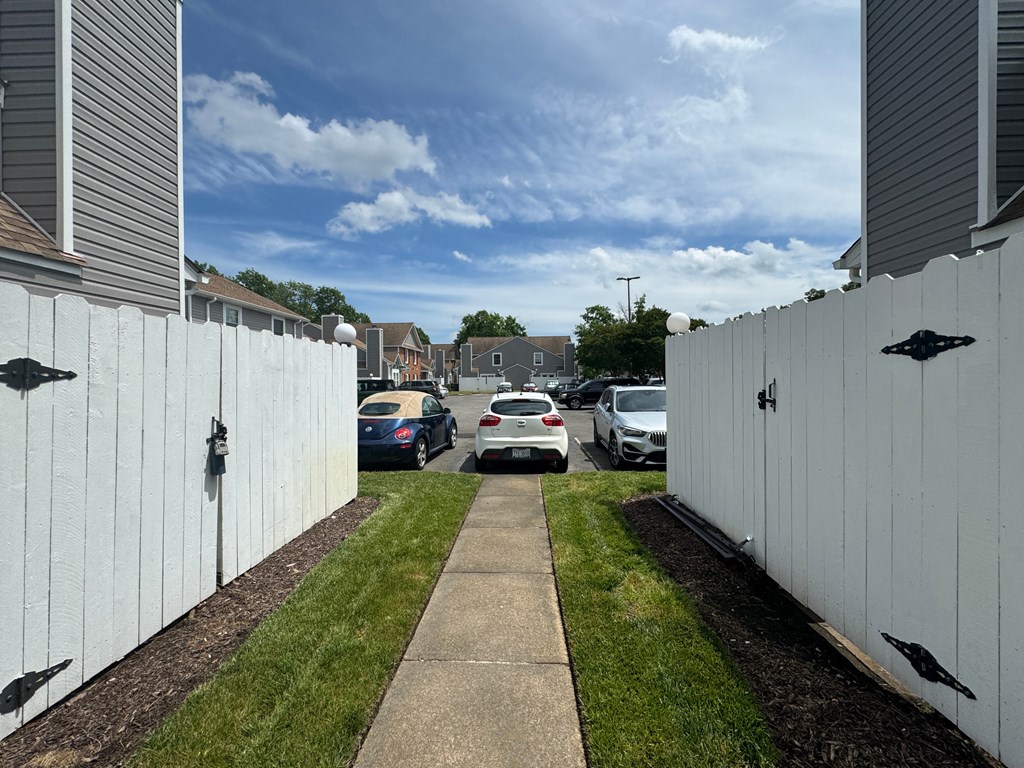 a white fence with cars parked in a parking lot
