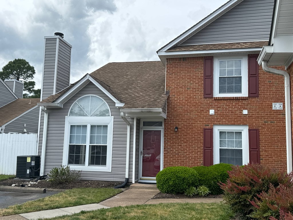 a brick house with a red door and white windows