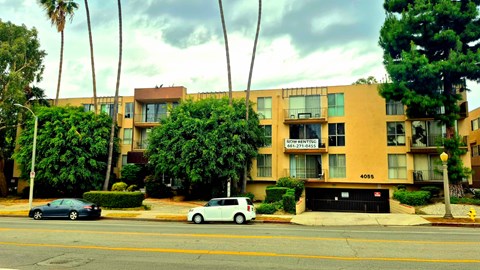 A white car is parked in front of a building with the number 4055 on it.