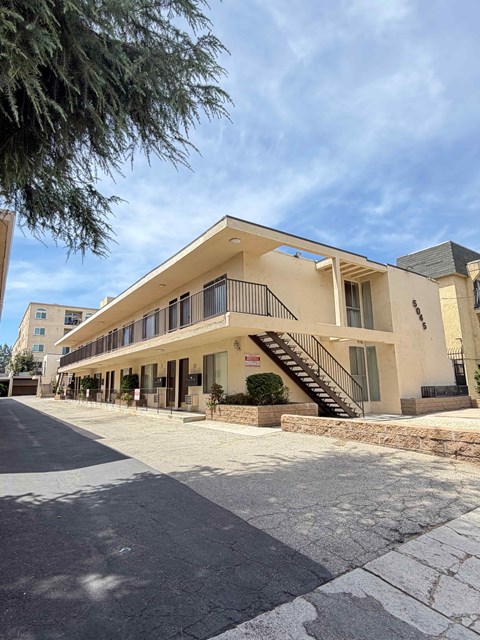 A modern building with a flat roof and a balcony on the second floor.