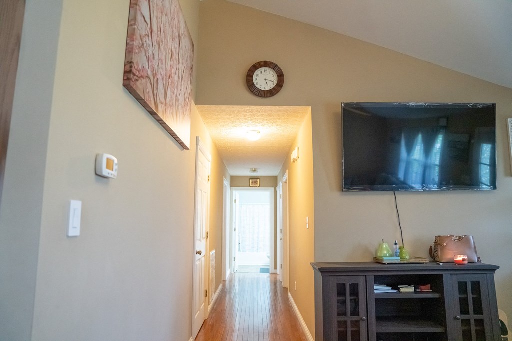 a long hallway with a tv on the wall and a door to a room