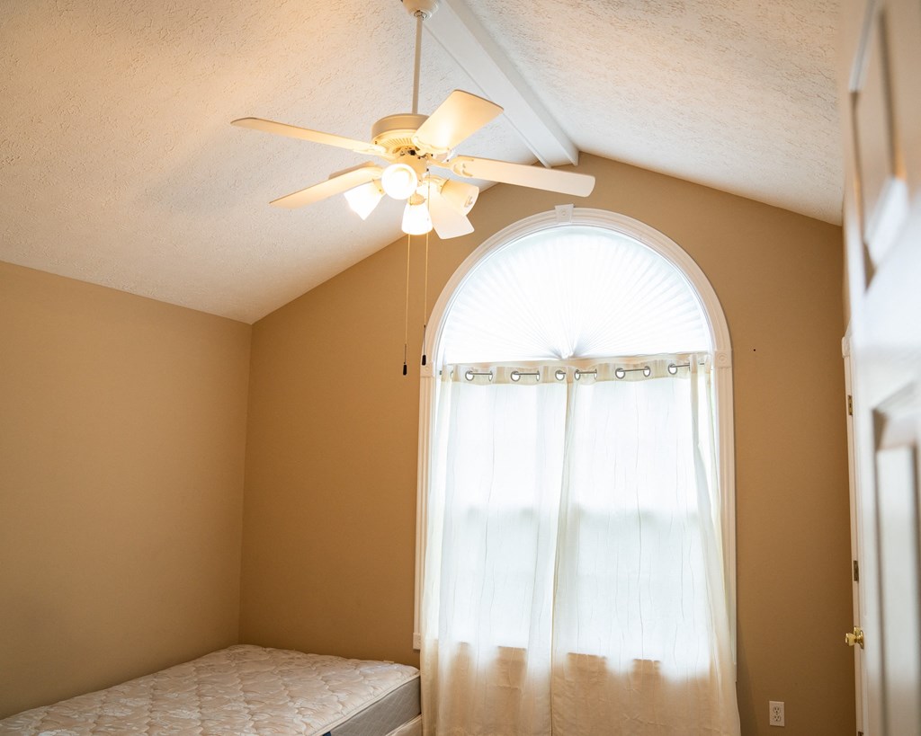 a bedroom with a ceiling fan and a window