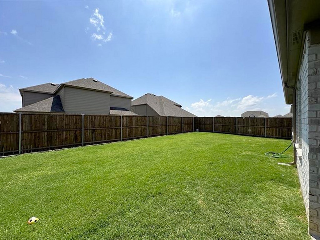 a backyard with a fence and a green lawn