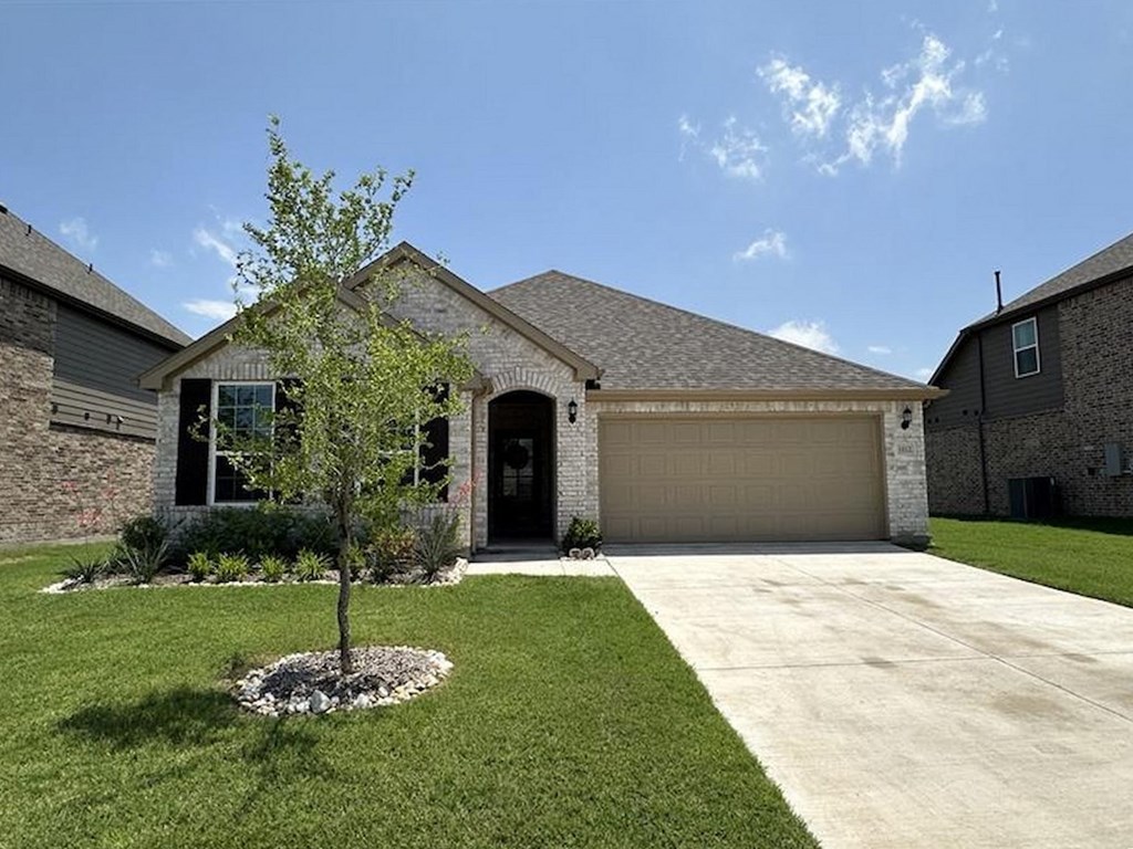 a house with a driveway and a tree in front of it