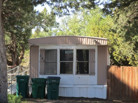 a tiny house with trash cans in front of it