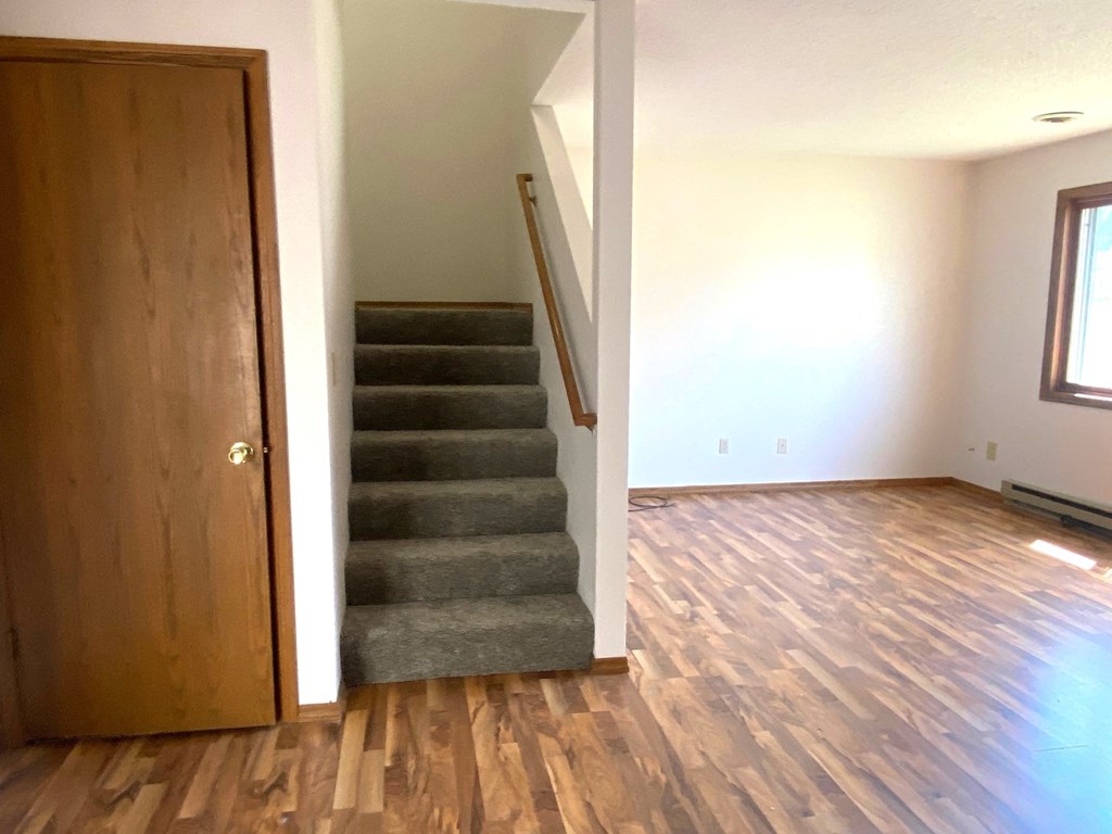 a view of a staircase in a house with wood floors and a door