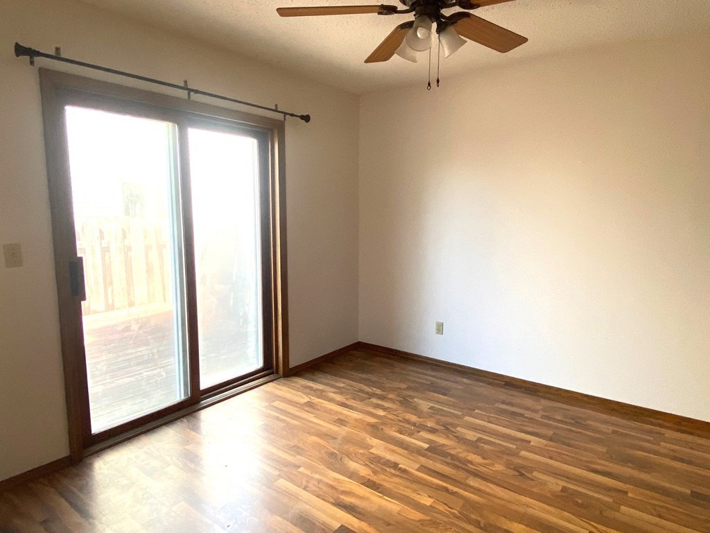 an empty living room with wood floors and a sliding glass door