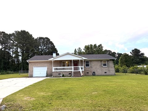 a small brick house with a yard and a white garage door