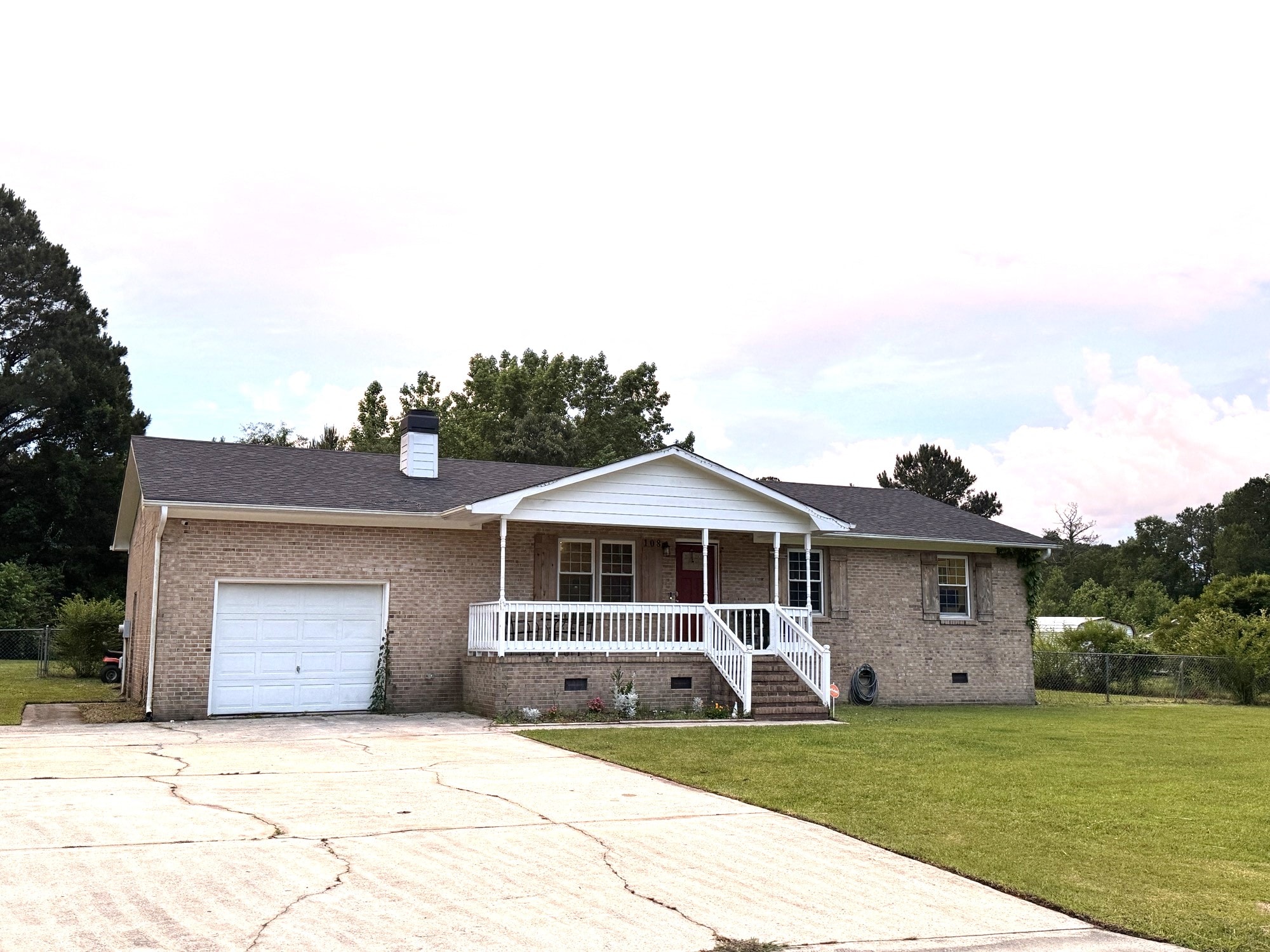a brick house with a white porch and a white garage door