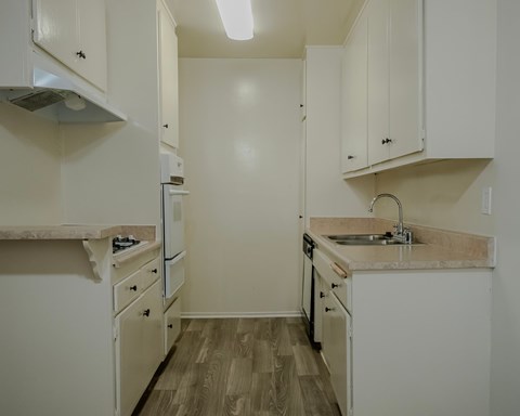 A kitchen with white cabinets and a wooden floor.