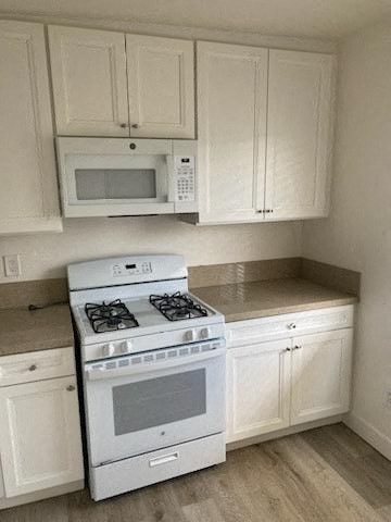 a white kitchen with a stove and a microwave
