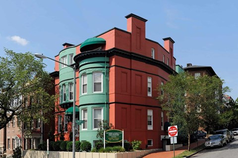 A red and green building with a sign in front.