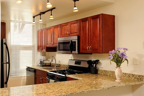 A kitchen with brown cabinets and granite countertops.
