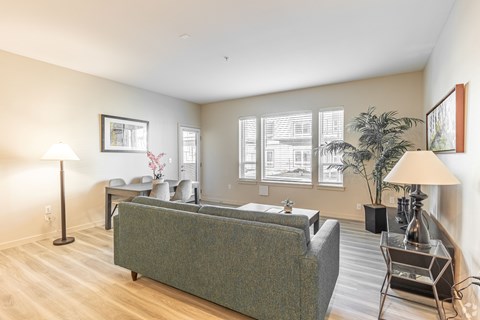 A living room with a grey couch and a lamp.