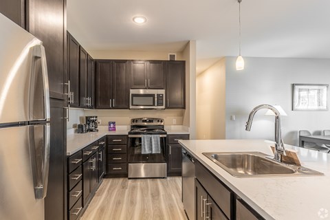 A modern kitchen with dark wood cabinets and stainless steel appliances.