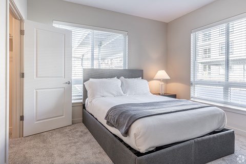 A bedroom with a large bed and a window with blinds.