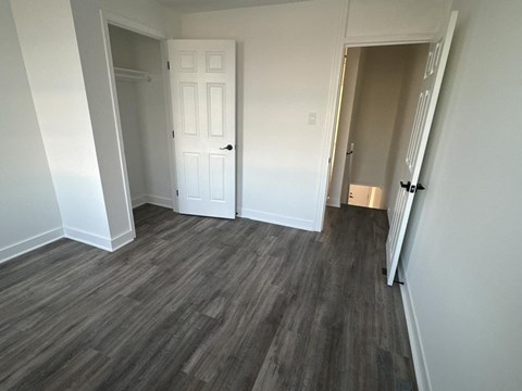 a bedroom with a door and a hallway with wood flooring