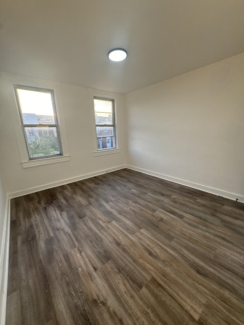 an empty living room with wooden floors and a window