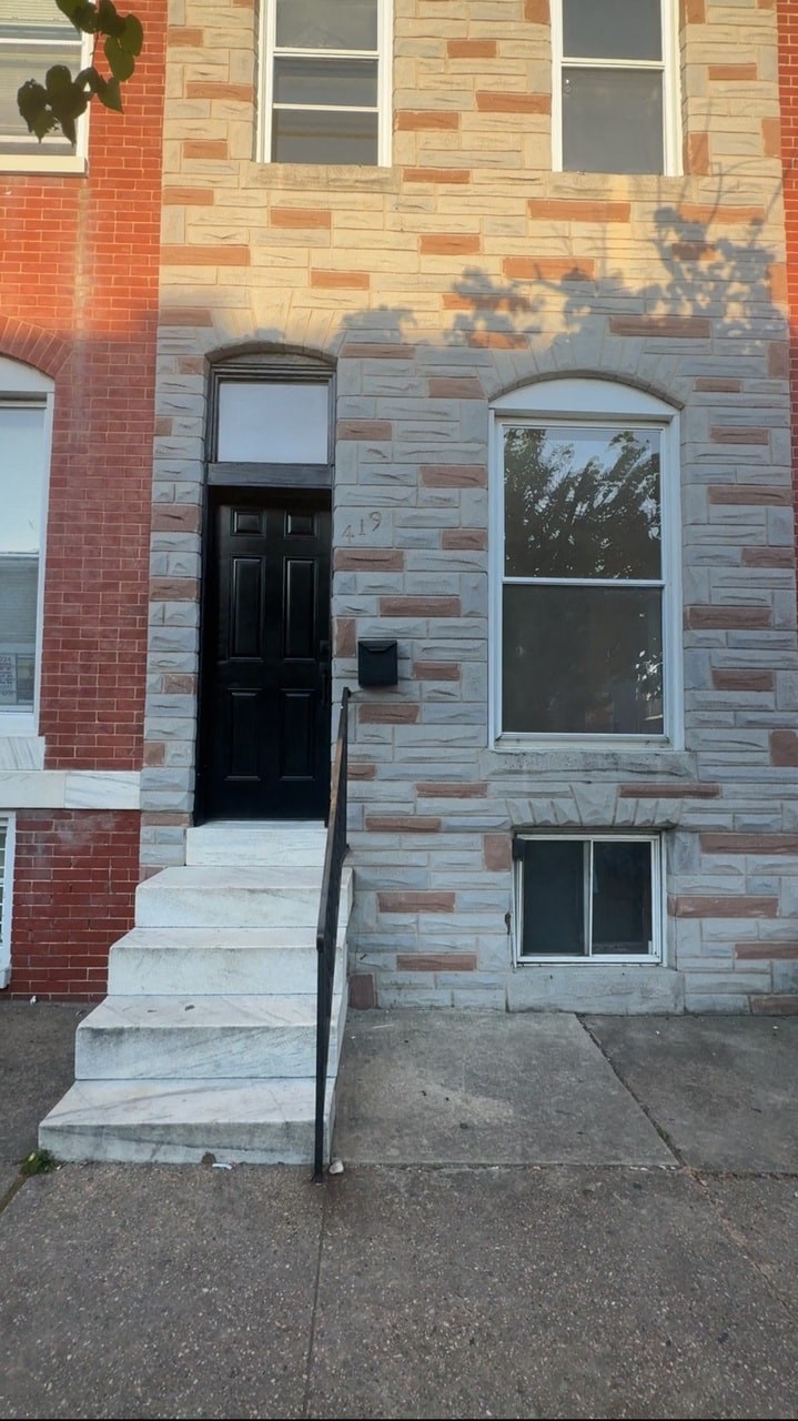 the front of a brick building with a black door and stairs