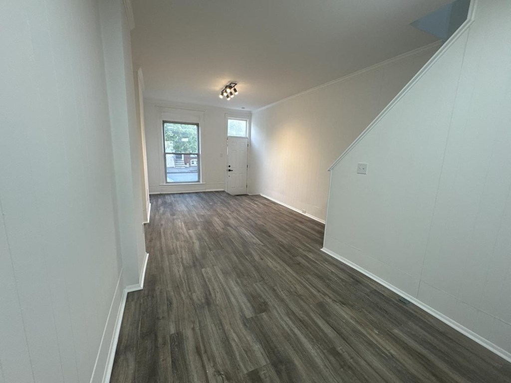 a living room and hallway with white walls and wood floors
