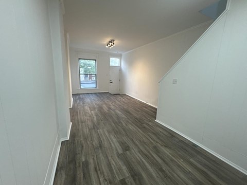 a living room and hallway with white walls and wood floors