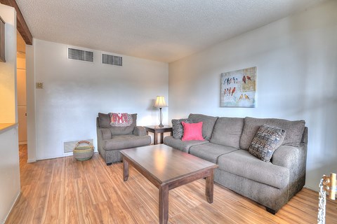 A living room with a grey couch and a wooden coffee table.