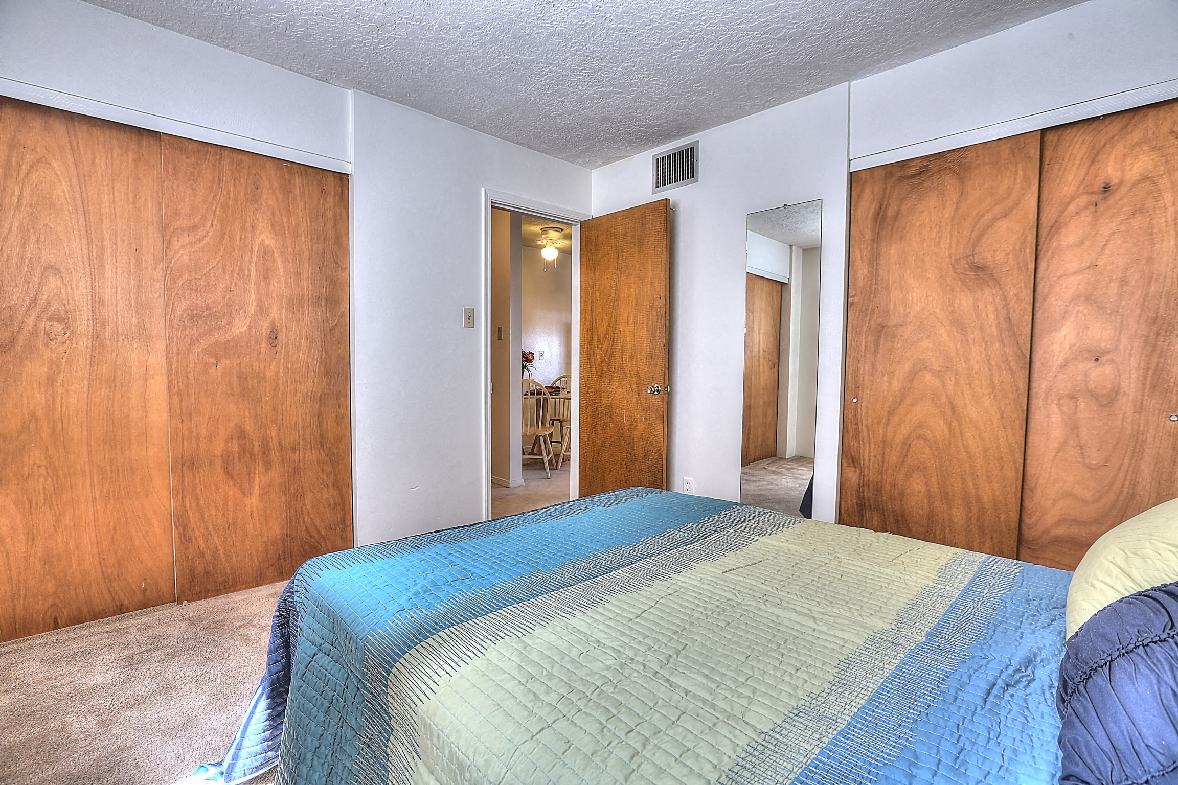 A bedroom with a bed in the center and wooden walls.