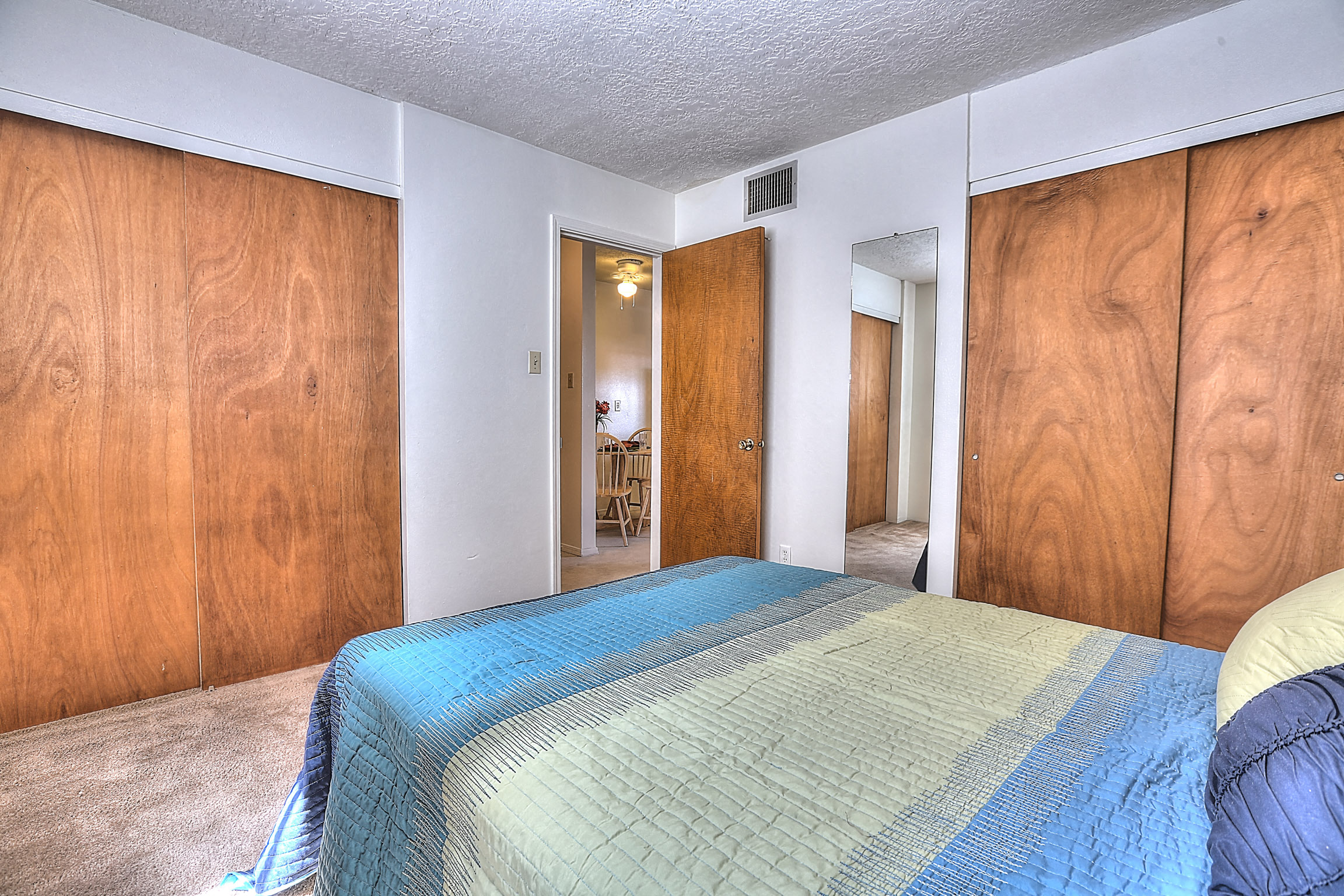 A bedroom with a bed in the center and wooden walls.