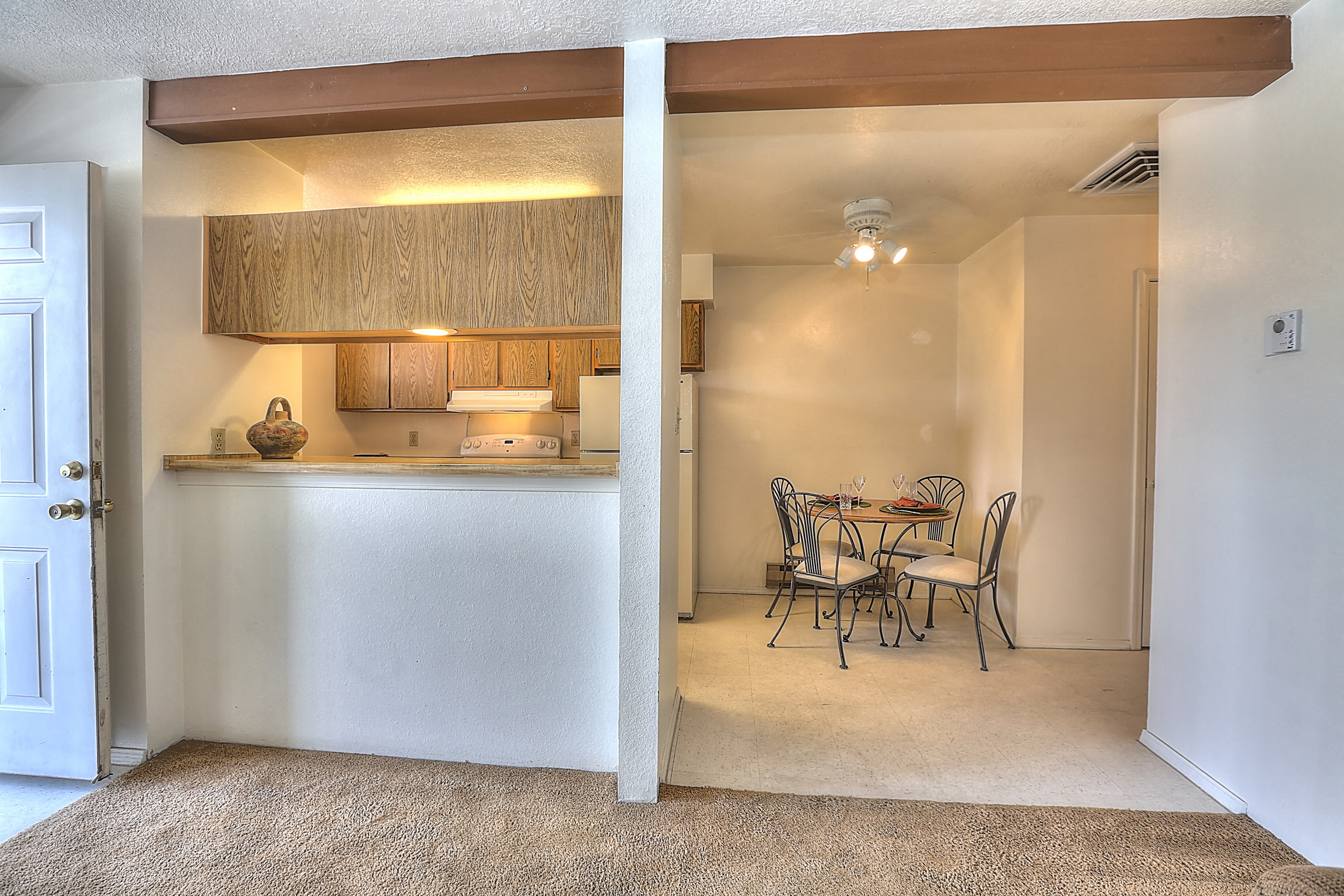 A kitchen with a dining table and chairs is visible through a doorway.