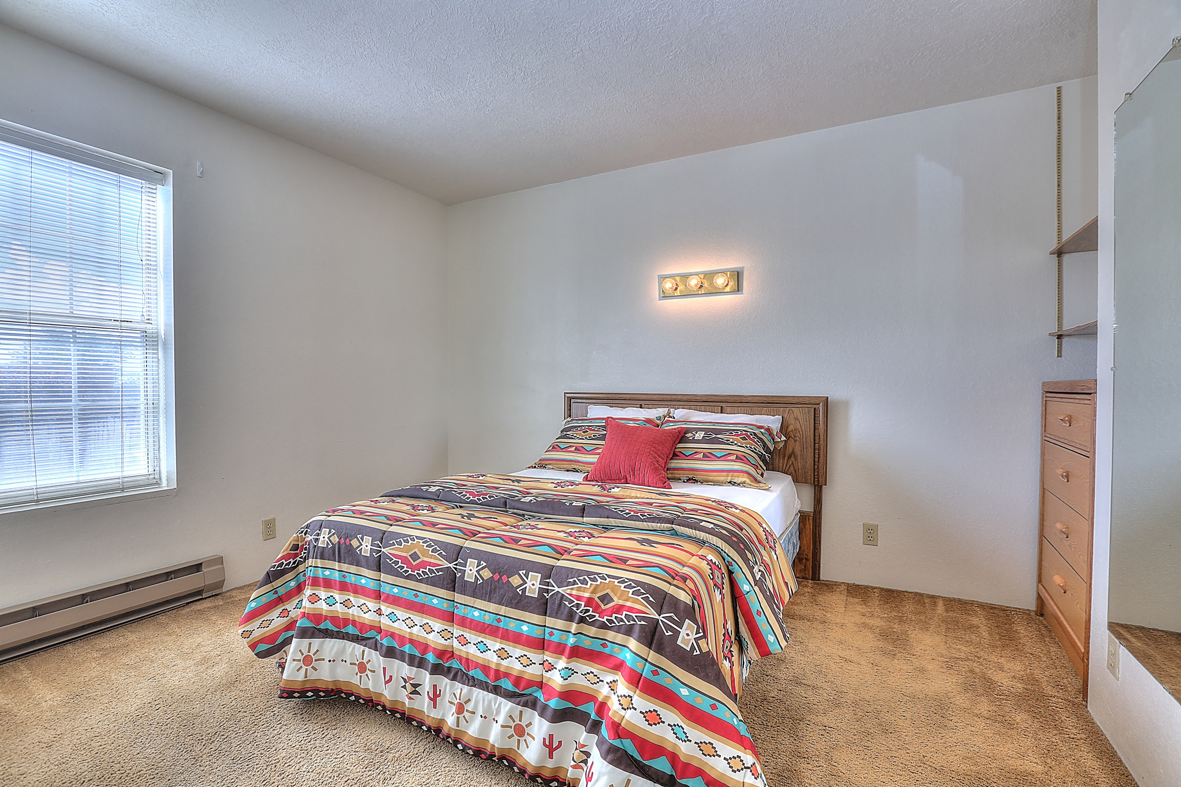 A bedroom with a bed covered in a colorful comforter.