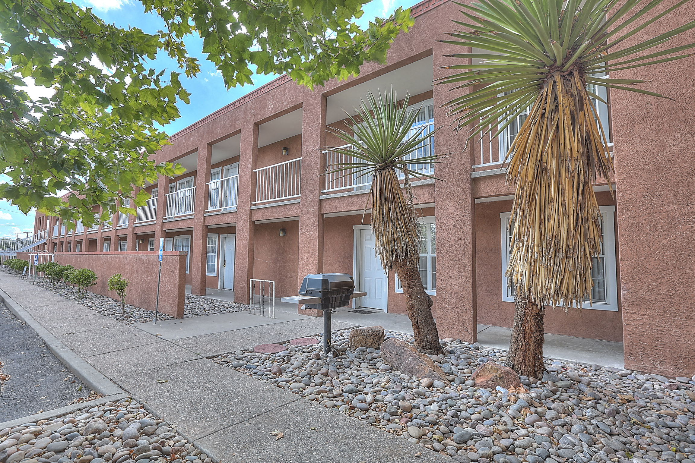 A red brick building with a mailbox and two palm trees in front.