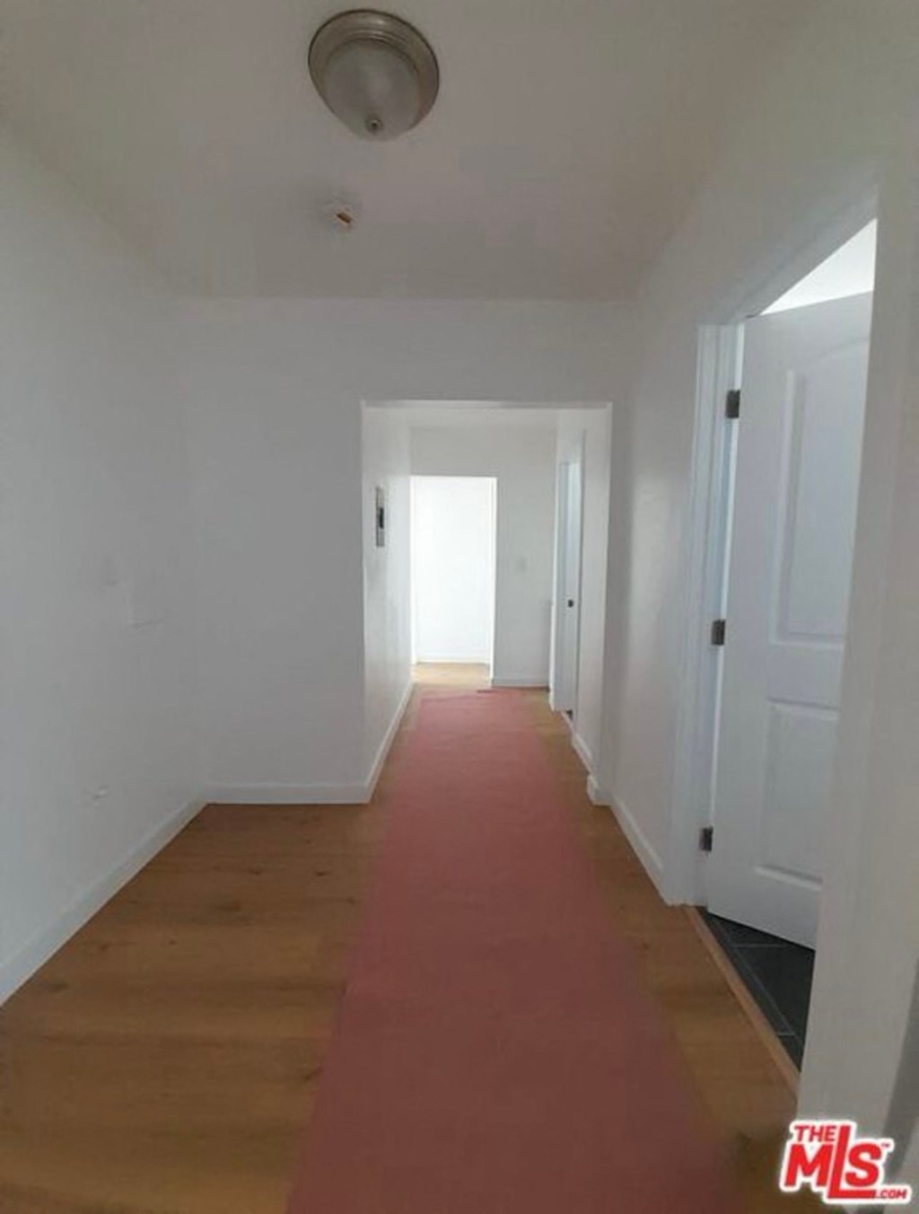 a hallway with a red carpet and white walls and doors