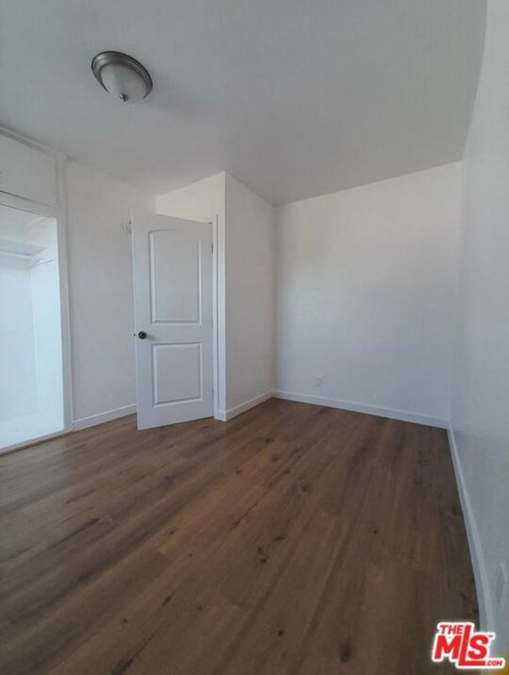 a empty room with white walls and wooden floors