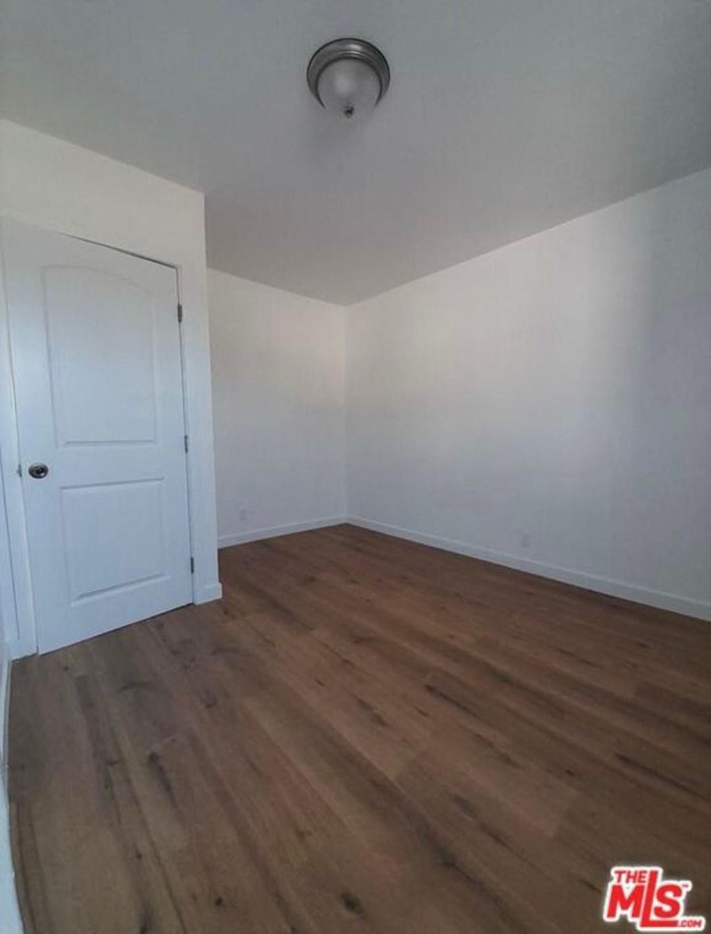 a empty room with white walls and wooden floors