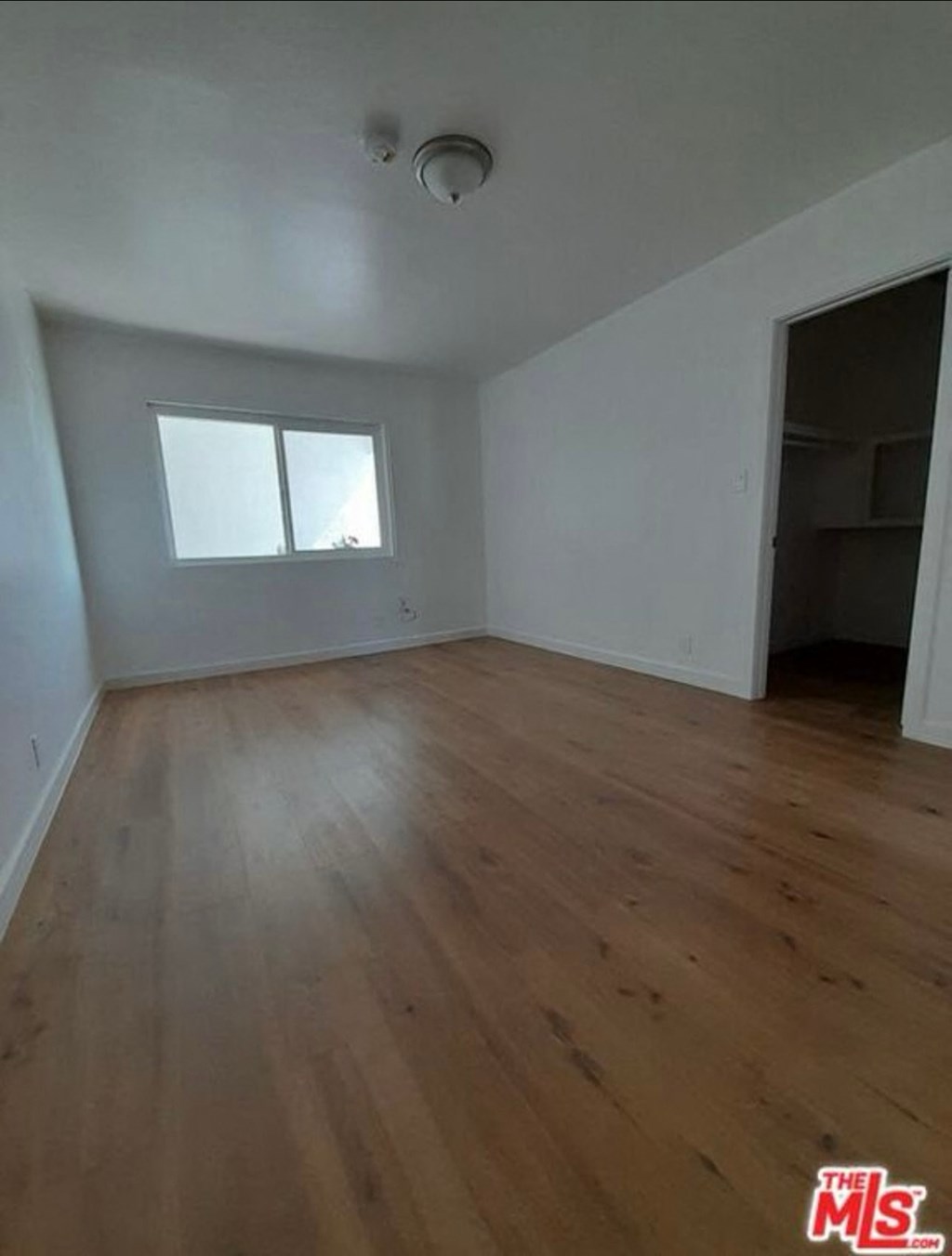 an empty living room with wood floors and a window