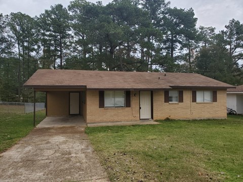 a small brown house with a dirt road in front of it
