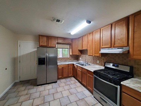 an empty kitchen with stainless steel appliances and wooden cabinets