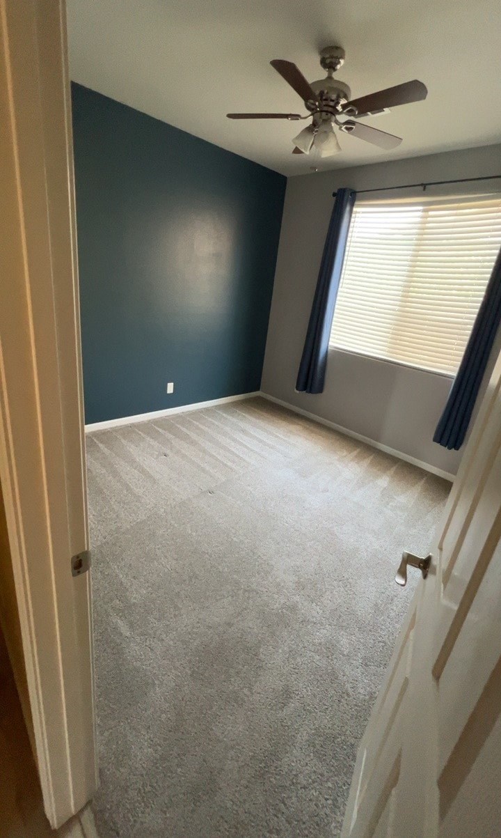 an empty room with a ceiling fan and a window